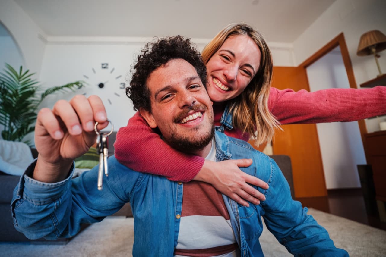 A couple smiling, holding the keys to their new home.